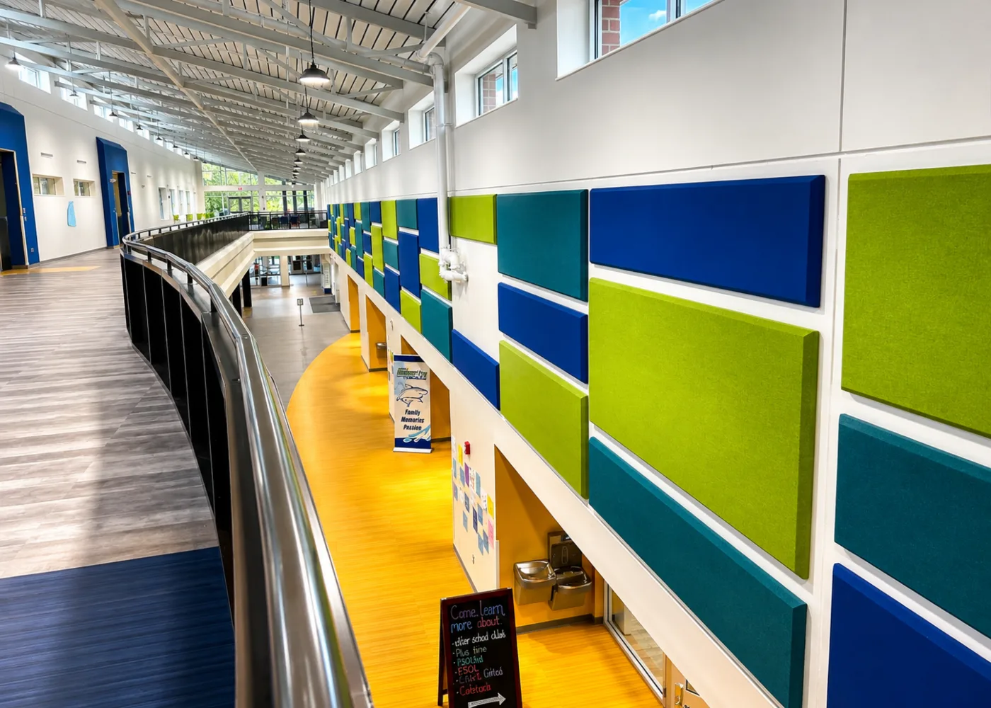 Staggered colorful acoustic wall panels above a curved balcony corridor at North River Middle School in Florida