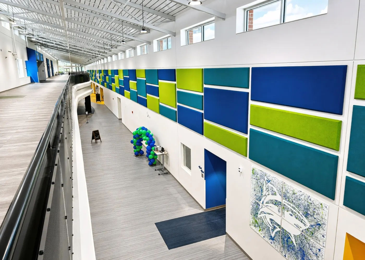 Rows of blue and green echo-reducing acoustic panels along a two-story corridor at North River Middle School